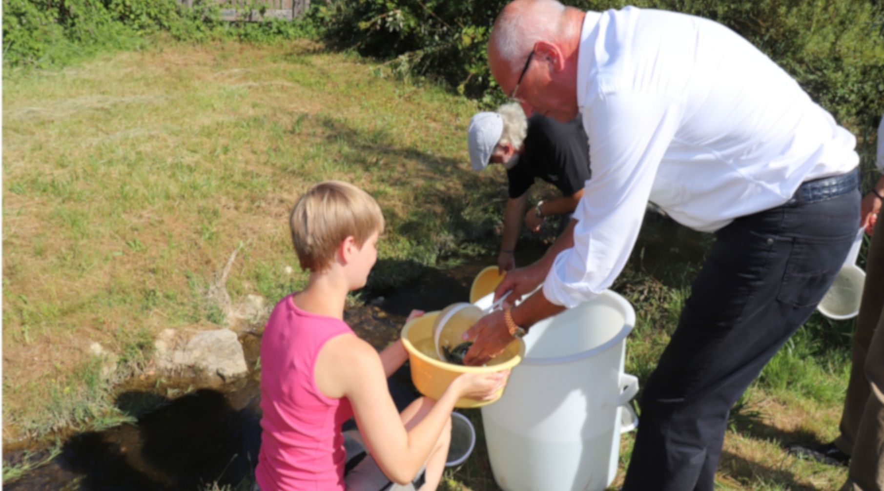 Ab in den Safaribach! Bezirkstagspräsident Dr. Günther Denzler und Friedrich Schmauser setzten mit Fischwirtin Alina Großmann 1.000 kleine Forellen in die Aufseß ein.
