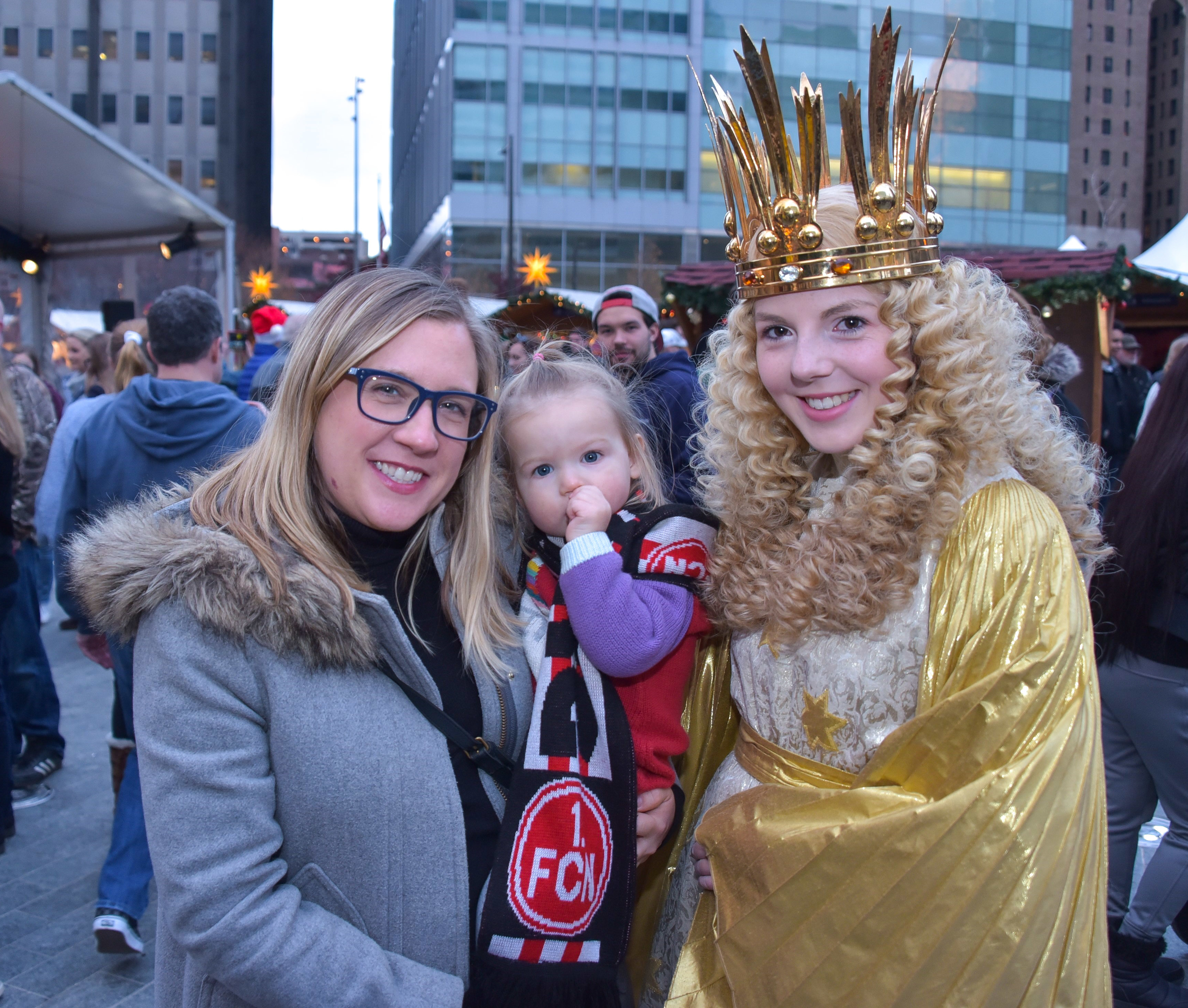 Das Nürnberger Christkind der Jahre 2015/16, Barbara Otto, mit der kleinen Mae und Maes Mutter im Christmas Village in Philadelphia. Maes Vater ist Nürnberger und bekennender Club-Fan. Sein Fan-Schal steht auch bei der Tochter hoch im Kurs.