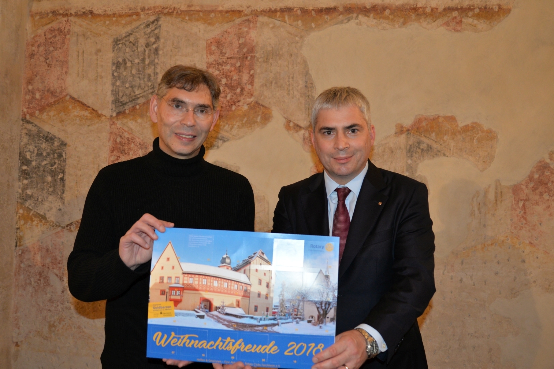 Pfarrer Christian Muschler von der Christusgemeinde Forchheim und Dr. Michael Waasner mit dem Adventskalender „Helfen und Gewinnen - Weihnachtsfreude 2018“ des Rotary Club Forchheim (v.l.).