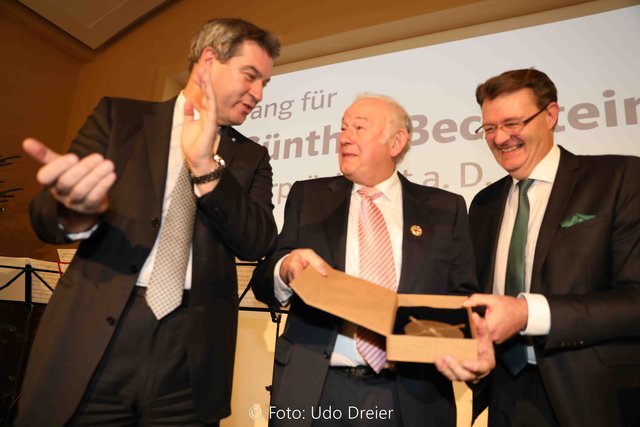 Ministerpräsident Dr. Markus Söder (li.) und Bundestagsabgeordneter Michael Frieser überreichen Günther Beckstein ein Gesangbuch und ein Holzkreuz als Geschenk. | Foto: © Udo Dreier