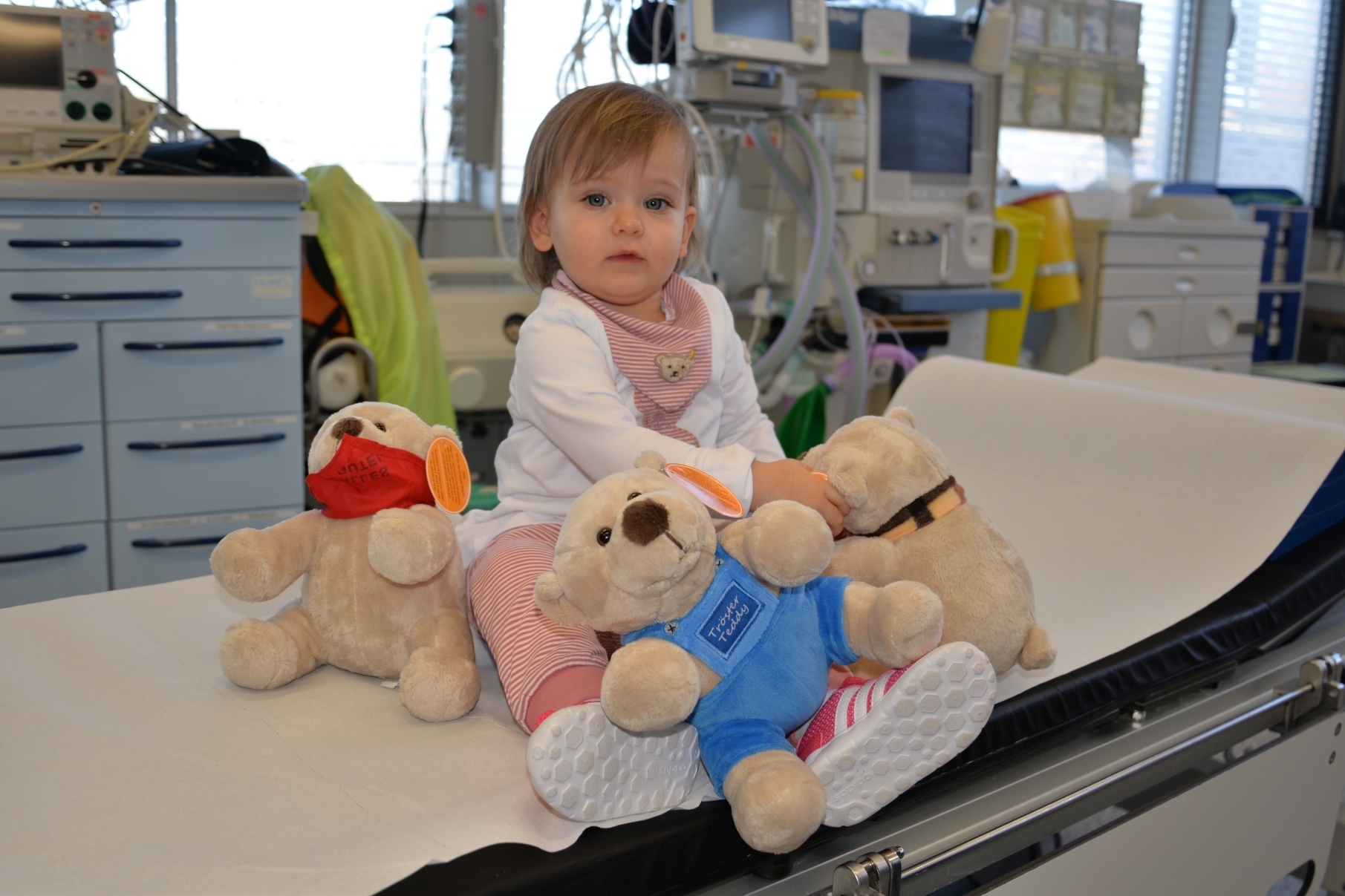Die kleine Leni kann sich nicht entscheiden – am liebsten würde sie mit allen drei Teddybären spielen.