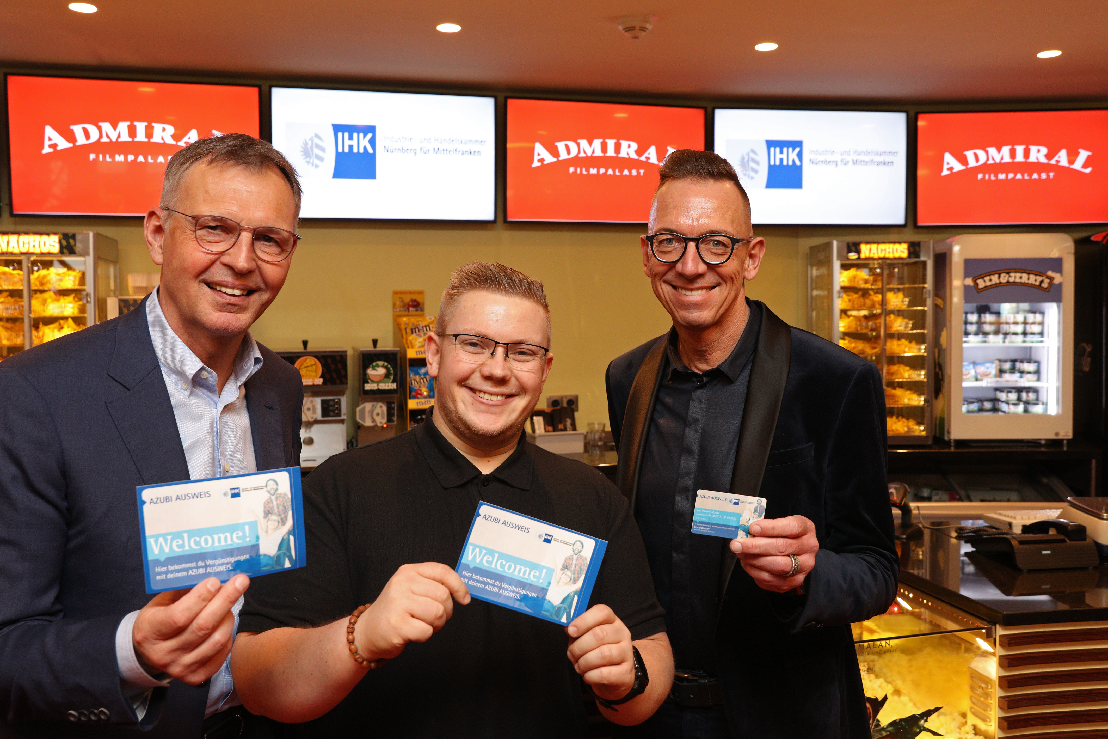 ,,AZUBI AUSWEIS Welcome!": Der erste Aufkleber, mit dem Unternehmen künftig auf Vergünstigungen für Inhaber des Azubi-Ausweises hinweisen können, wurde von IHK-Präsident Dirk von Vopelius (l.) und Stefan Kastner, Leiter des IHK-Geschäftsbereichs Berufsbildung, an Christian Schwan, technischer Leiter des Admiral Filmpalasts in Nürnberg (Mitte), überreicht. Im ,,Admiral" können Azubis mit dem Ausweis Filme für fünf Euro sehen (außer samstags abends und sonntags abends).