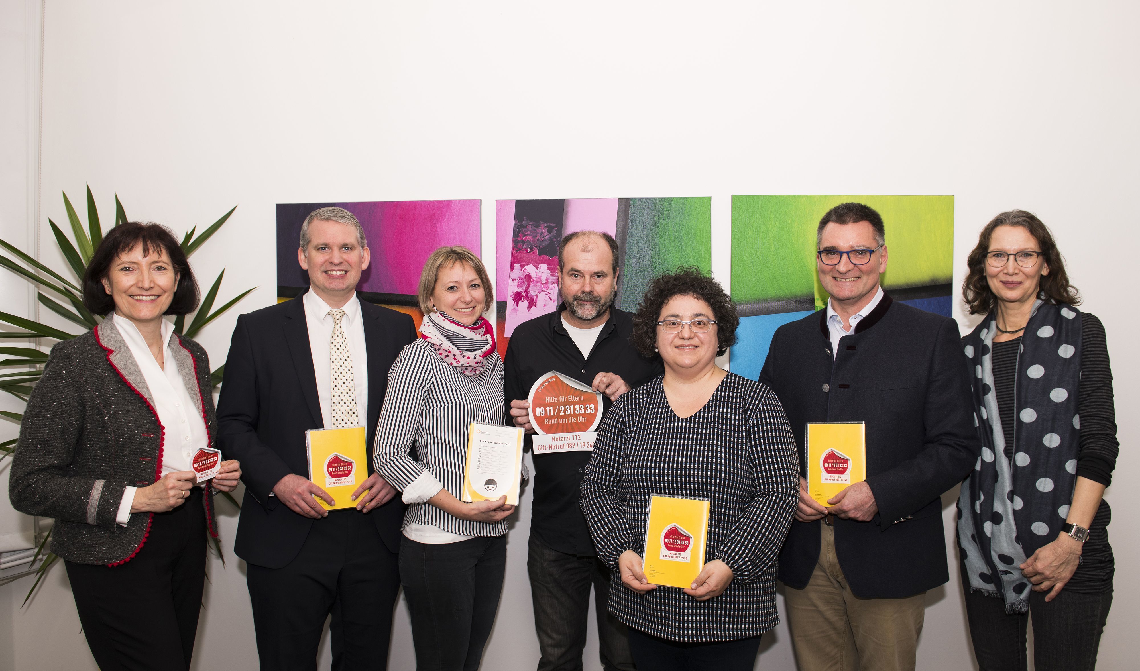 Kerstin Schröder vom Jugendamt, Christian Löhberg und Marion Helfrich vom St. Theresien-Krankenhaus, Wolfgang Köhler vom Klinikum Nürnberg, Melek Karagöz-Perst und Michael Schroth von der Klinik Hallerwiese/Cnopfsche Kinderklinik und Susanne Becke von der KoKi (v.l.) bei der Übergabe der mit der Hotline der Frühen Hilfen versehenen Umschläge und Aufkleber.