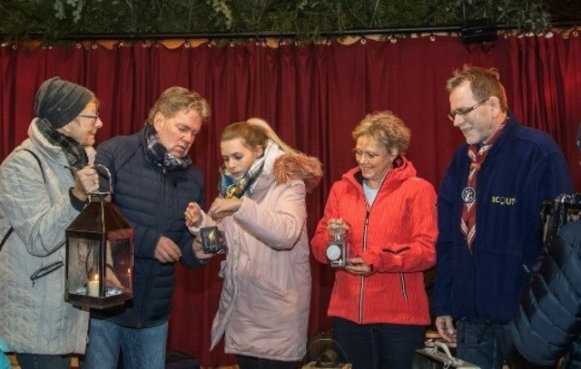Pfadfinderinnen und Pfadfinder überreichten Susanne Lender-Cassens (Erlanger Bürgermeisterin, zweite von rechts) und Ernst Stäblein (Organisator der Erlanger Waldweihnacht, zweiter von links) das Friedenslicht.