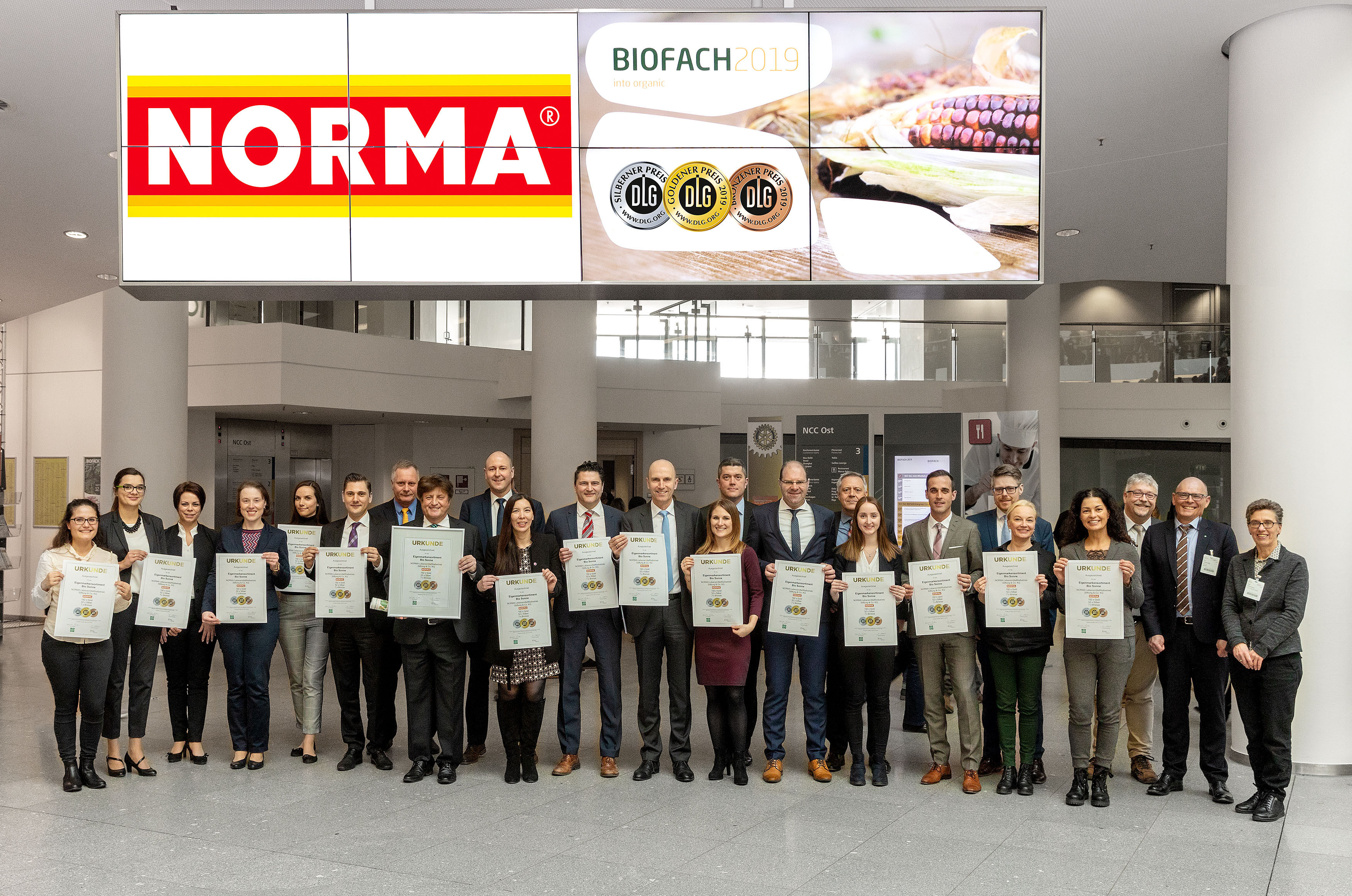 So sehen Dauersieger aus: Der im gesamten Bundesgebiet aktive Discounter NORMA ist und bleibt bester deutscher Bio-Händler, wie jetzt das Top-Abschneiden beim großen Bio-Qualitätstest der Deutschen Landwirtschafts-Gesellschaft (DLG) auf der Biofach wieder beweist. Denn: Auf der Weltleitmesse für biologisch erzeugte Lebensmittel nahm das NORMA-Management zum zehnten Mal in Folge die Urkunden für die meisten DLG-Medaillen in Empfang – keinem anderen deutschen Handelsunternehmen gelingt es, für seine Kunden so viel ausgezeichnete Bio-Qualität in den Regalen zu platzieren. Auf unserem Bild ist das NORMA-Management inklusive der Geschäftsleitung und dem NORMA-Vorstand Gerd Köber (achter von links) zu sehen.