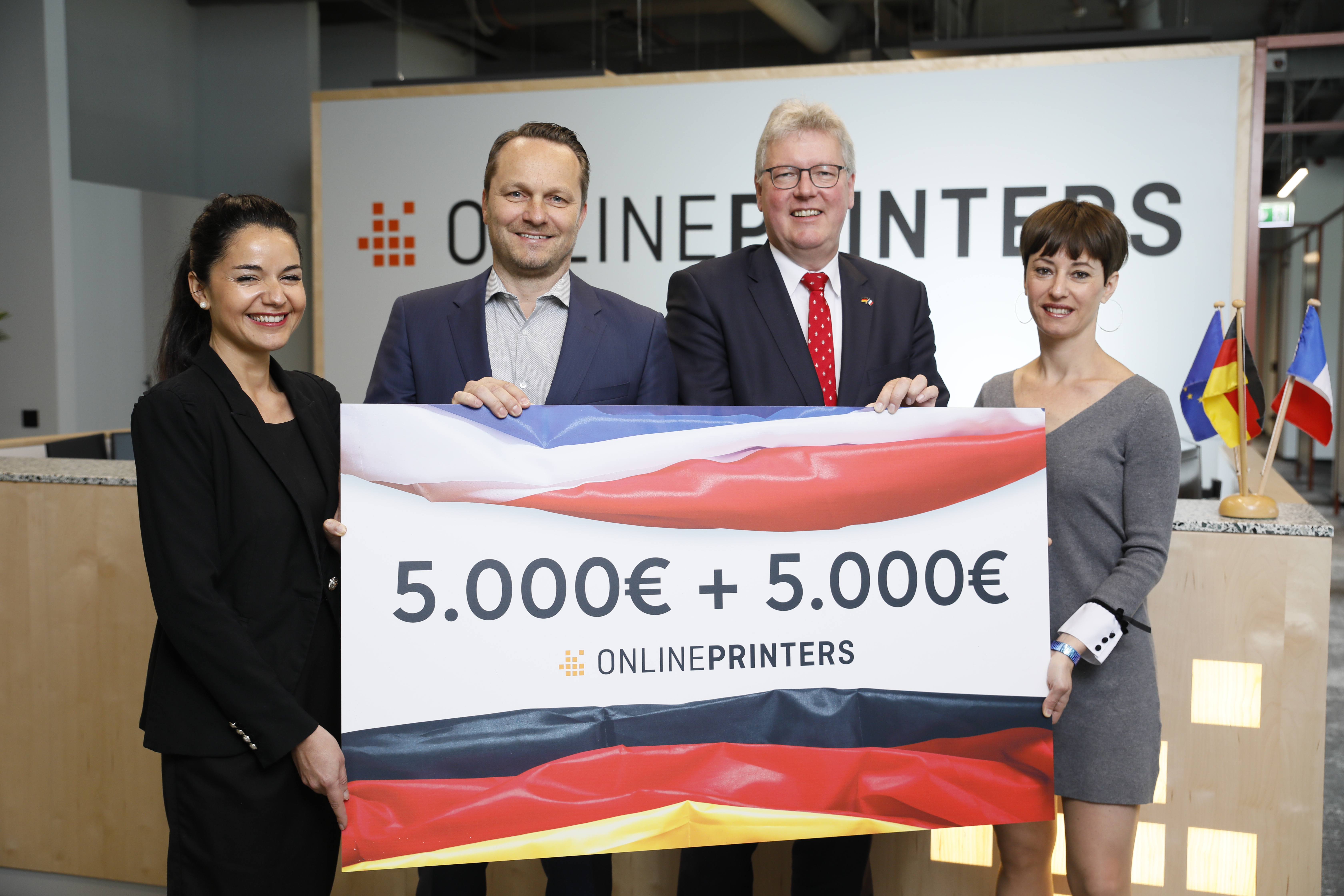 (v.l.) Cécile Assayag-Zimmermann, Marketing Managerin bei Onlineprinters, Dirk A. Müller, CFO der Onlineprinters-Gruppe, und Cécile Delorme, Leitung Brand Management (r.), übergeben Honorarkonsul Dr. Matthias Everding (2. v.r.) einen symbolischen Scheck in Höhe von insgesamt 10.000 Euro - die Hälfte davon fließt in den Wiederaufbau der Kathedrale Notre-Dame, die anderen 5.000 Euro werden für den deutsch-französischen Schüleraustausch verwendet.