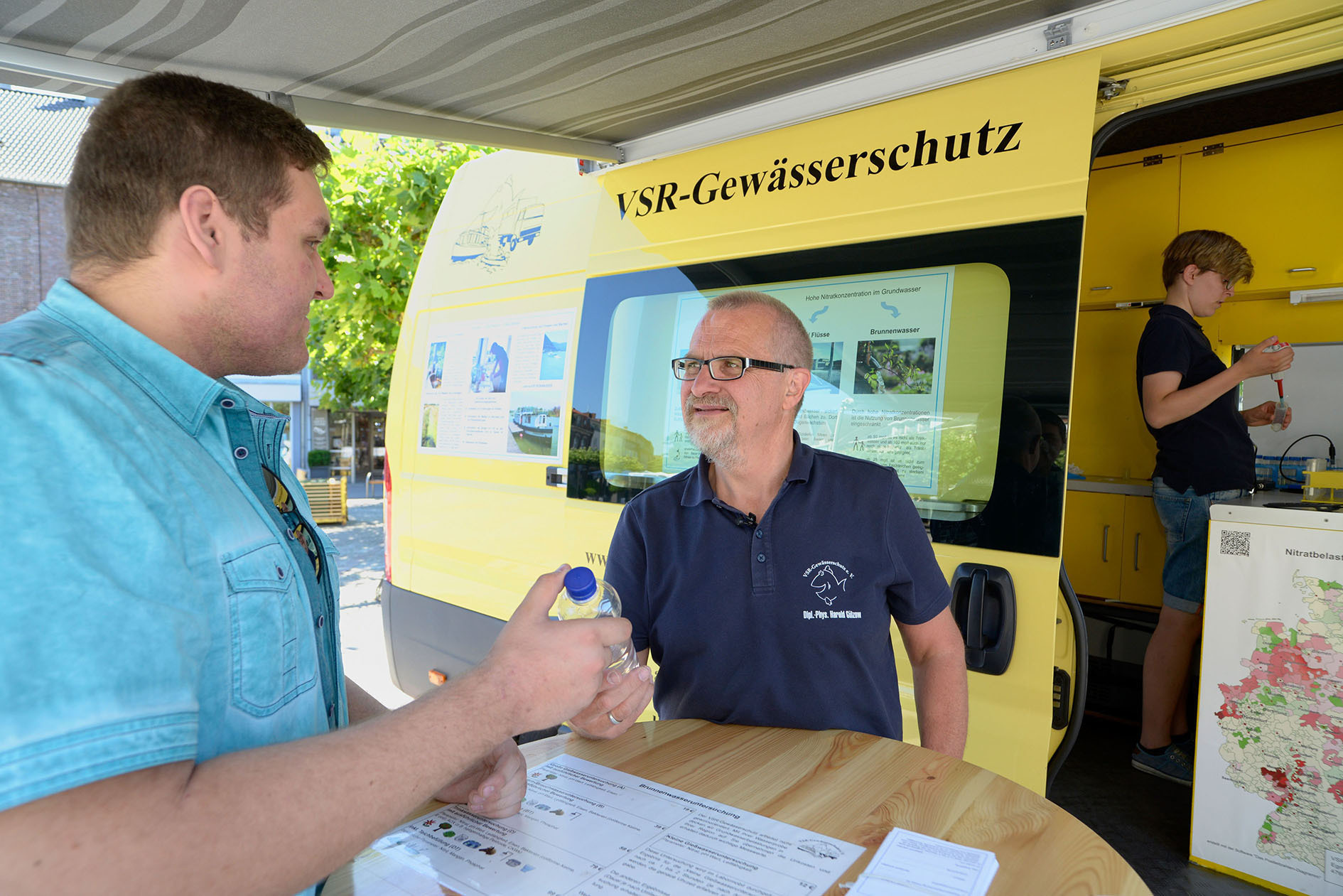 Harald Gülzow (r.) nimmt die Probe eines Brunnennutzers am Labormobil entgegen.