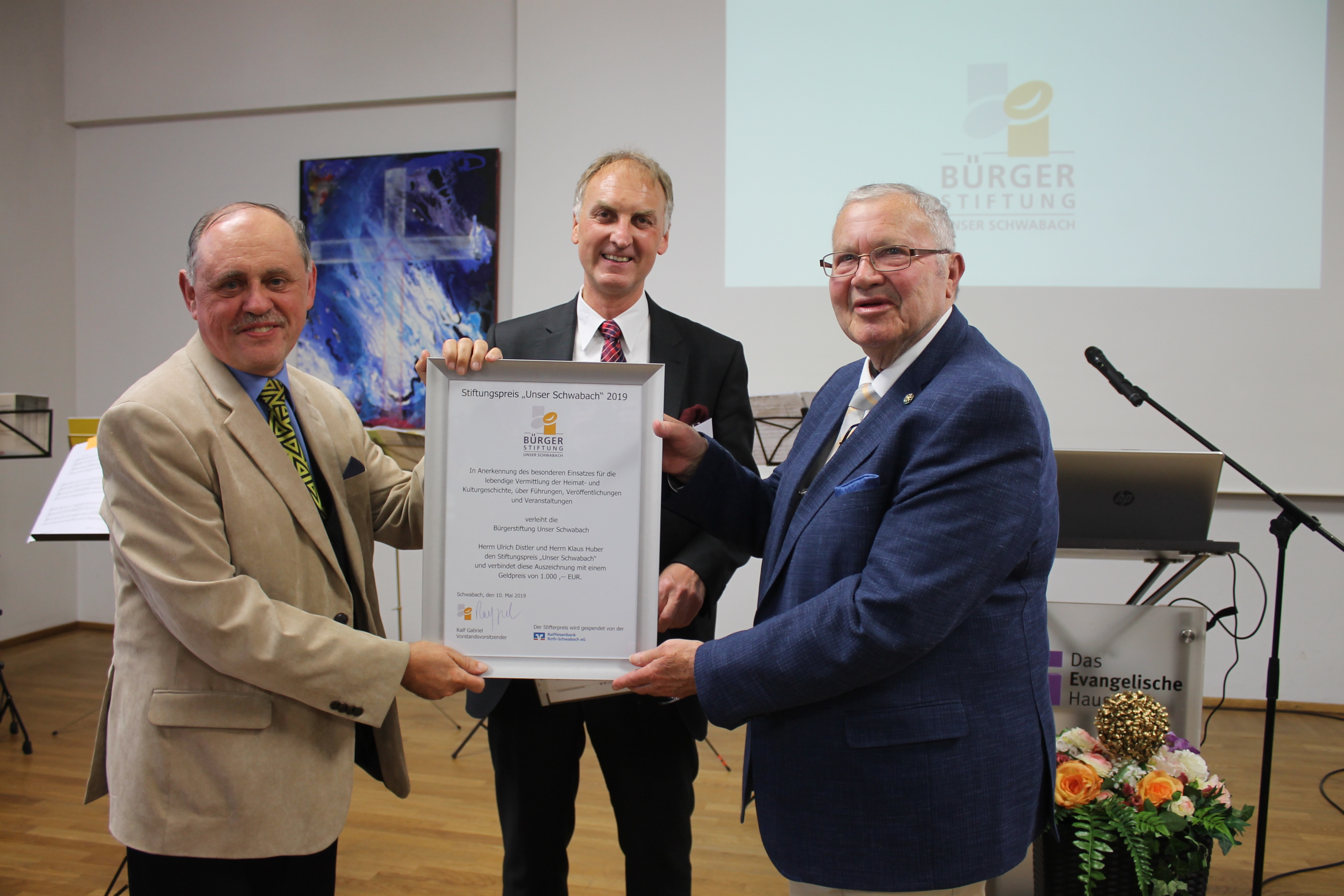 Ralf Gabriel (M.) überreicht im Saal des Evangelischen Hauses in Schwabach den Stiftungspreis "Unser Schwabach" 2019 an Ulrich Distler (l.) und Klaus Huber.