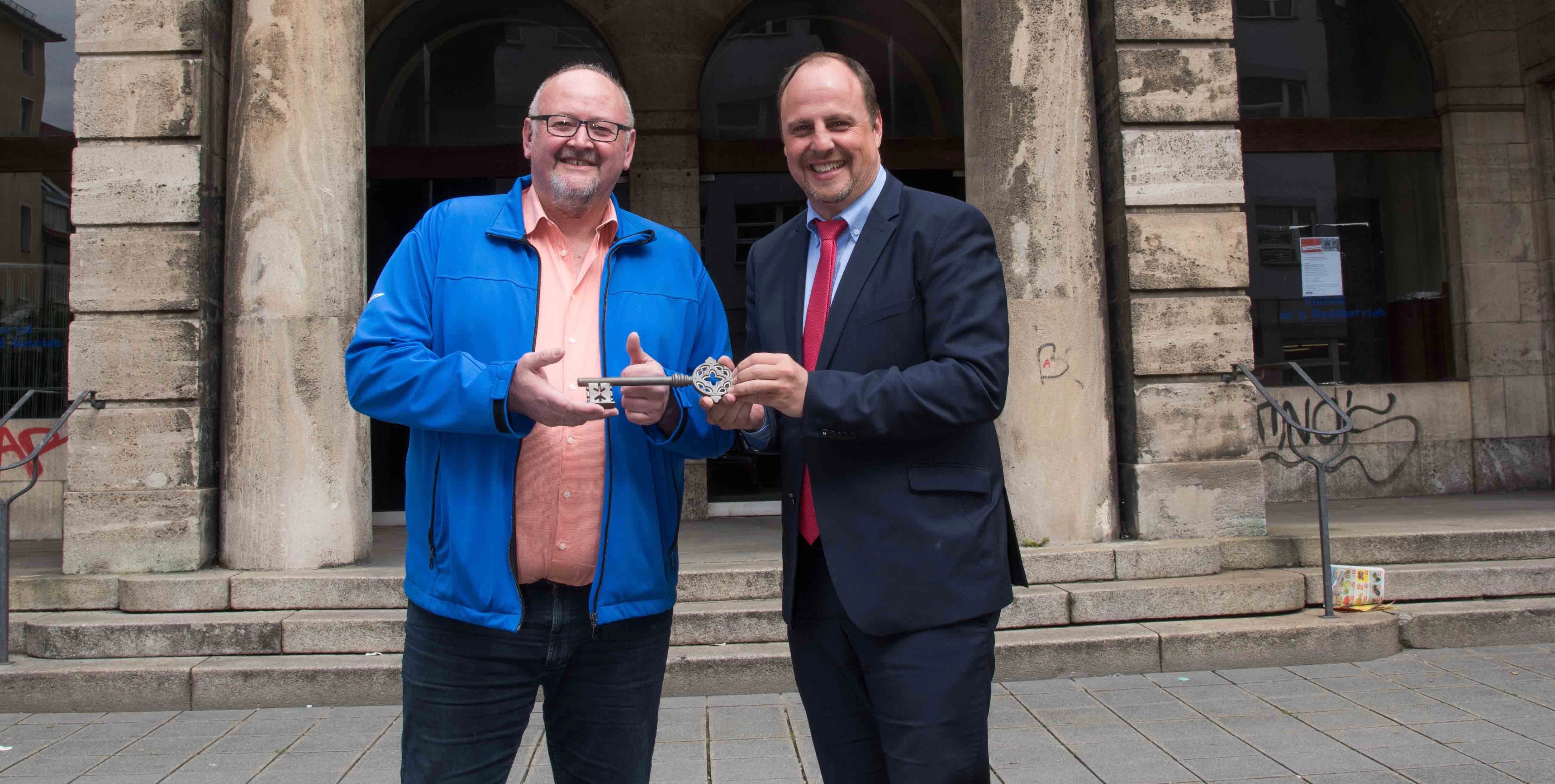 Bürgermeister Christian Vogel (r.) und der Projektleiter Sanierung Volksbad, Joachim Lächele, bei der symbolischen Schlüsselübergabe vor dem Eingang zum Volksbad in der Rothenburger Straße.