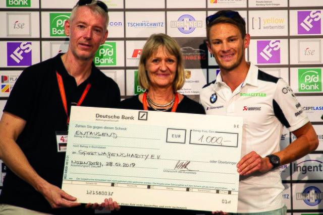 DTM-Champion Marco Wittmann (r.) überreichte den Spendenscheck von BMW Motorsport an die Organisatoren der Sportwagenchartiy Nürnberg, Alexander Heckel (Vorstand Sportwagencharity e.V.) und Annett Obermeyer.