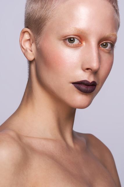 Beauty Looks: Neben dem stark glänzenden Teint steht der Mund hier ganz klar im Fokus: Die Lippen in einem ultra-matten und sehr dunklem Beerenton sind der Garant für einen Wow-Auftritt. Die Augen werden im Innenwinkel mit einem kräftigen Orange betont, sind ansonsten aber nahezu ungeschminkt. Die Bleached Brows vervollständigen das futuristische und moderne Make-Up und sind ein echtes Statement.  | Foto: © ZV Friseurhandwerk