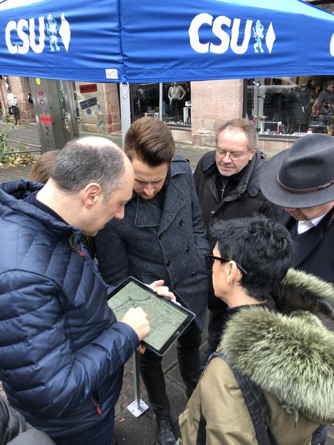 CSU-Stadtrat Andreas Krieglstein (l.) zeigt Besuchern des Infostandes, welche Bereiche der Altstadt betroffen sind von den Beschlüssen, die im nächsten Verkehrsausschuss gefällt werden.