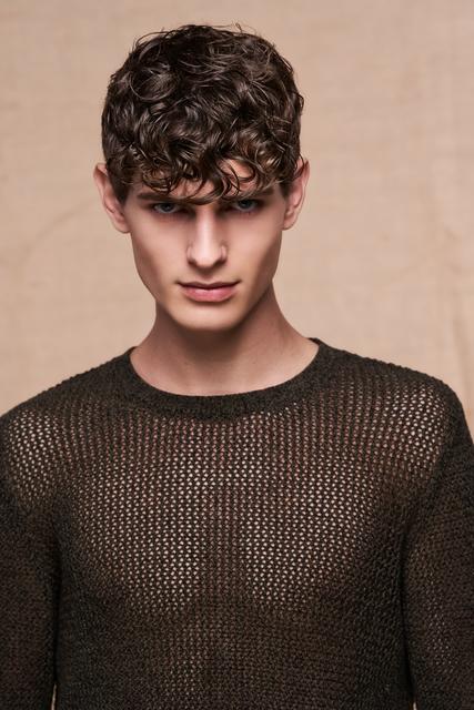 In der lockig gegelten Variante wirkt der Look dank dem längeren Deckhaar richtig lässig. Der Pony in Überlänge wird mit passenden Stylingprodukten in Form gebracht und gecurlt bis zu den Augenbrauen in die Stirn gelegt. Geswirlte Locken sind diese Saison unser ständiger Begleiter. | Foto: © Zentralverband Friseurhandwerk/Mario Naegler