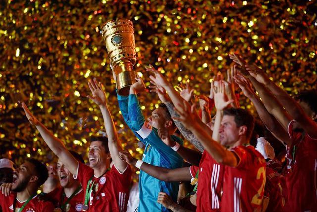Münchens Torhüter Manuel Neuer hält die Trophäe jubelt mit dem DFB-Pokal.