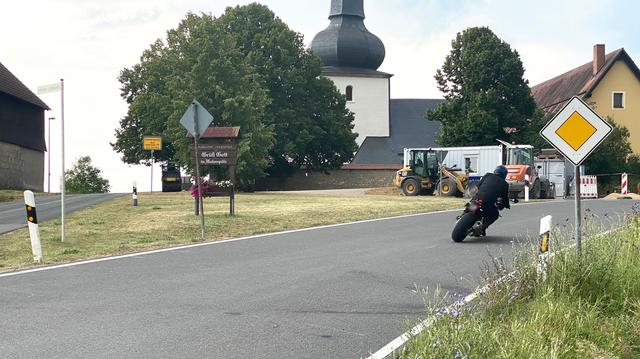 Der Tag danach. Die Spuren und Markierungen sind noch auf der Straße zu sehen, da fährt der nächste Motorradfahrer mit hoher Geschwindigkeit in die schmale Rechtskurve in den Ort hinein, wahrscheinlich unwissend, dass wenige Stunden zuvor ein Biker-Kollege genau hier gestorben ist. Die BA11 (von/nach Königsfeld) bis Hohenpölz ist eine beliebte Kurzrennstrecke für Motorradfahrer.