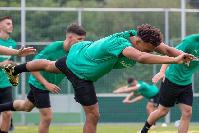 Der Spieler Jamie Leweling (M) dehnt sich auf dem Platz. | Foto: Daniel Karmann/dpa