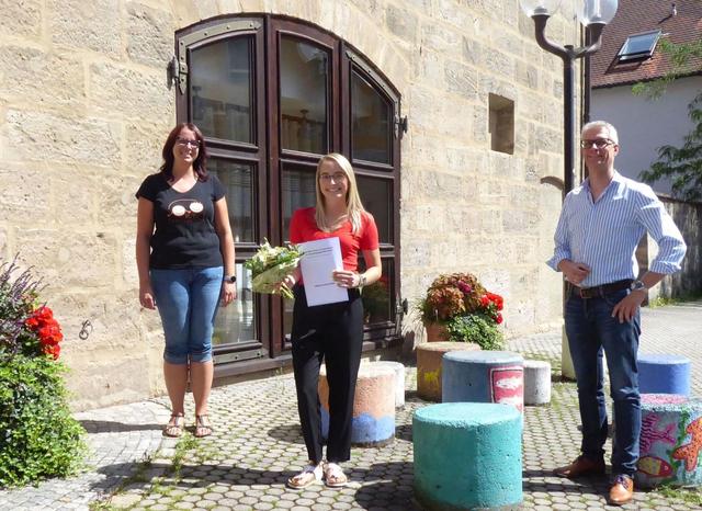 Giselle Kress (Mitte) freut sich zusammen mit Oberbürgermeister Dr. Uwe Kirschstein und ihrer Anleiterin Sarah Wiedow vom städtischen Kindergarten Sattlertor über ihren hervorragenden Abschluss als Kinderpflegerin.