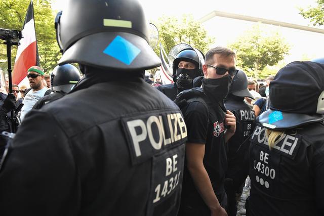 Während der Proteste gegen die Corona-Politik in Berlin ist es vereinzelt zu Rangeleien und Angriffen auf Einsatzkräfte der Polizei gekommen. Im Bereich der Reichstagswiese seien Teile der Absperrung umgeworfen worden, twitterte die Polizei. «Es drangen Personen in den gesperrten Bereich vor.» Dagegen sei die Polizei vorgegangen. Polizeisprecher Thilo Cablitz sagte dazu, dass es dort zu Rangeleien gekommen sei. Auf einer Bühne vor dem Reichstag hatte unter anderem der Vegan-Koch Attila Hildmann gesprochen, der immer wieder Verschwörungsmythen verbreitet. Vor der Russischen Botschaft versammelten sich laut Cablitz rund 2000 Menschen. Dort seien Einsatzkräfte angegriffen worden. Weitere Angaben dazu konnte er vorerst nicht machen. Bereits zuvor hatte die Polizei von Stein- und Flaschenwürfen auf Polizisten im Zusammenhang mit dem Demonstrationsgeschehen in der Stadt berichtet. | Foto: Bernd Von Jutrczenka/dpa