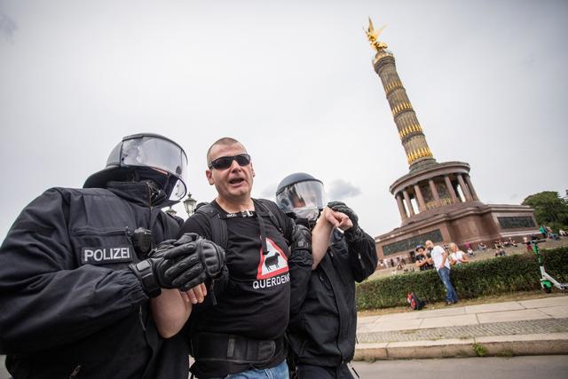 Ein Mann wird beim Protest gegen die Corona-Maßnahmen vor der Siegessäule von Polizisten abgeführt. | Foto: Christoph Soeder/dpa