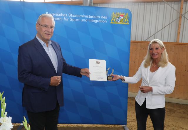 Bayerns Innenminister Joachim Herrmann überreicht die Urkunde zur Schirmherrschaft über Bayerns Reiterstaffeln an Karin Baumüller-Söder.  | Foto: Udo Dreier