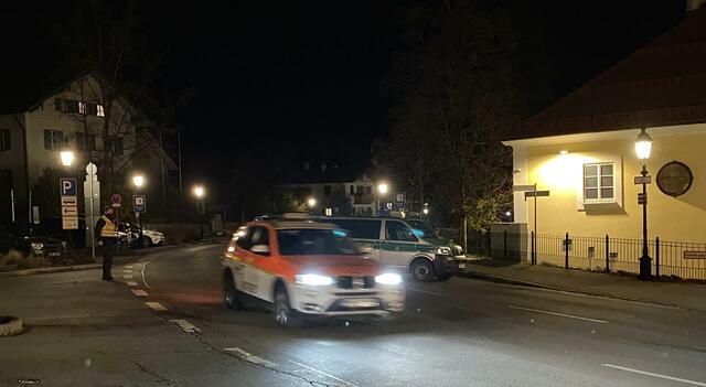 Ein Notarztfahrzeug und Polizeibeamte am Tatort der Geiselnahme in Tegernsee.  | Foto: Maxi Hartberger/Tegernseer Stimme/dpa