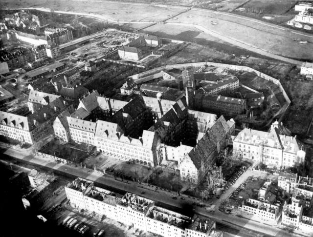 Der Nürnberger Justizpalast im Winter 1945/46, zu erkennen sind noch Kriegsschäden. Rechts, etwas zurückgesetzt, der Ostbau, in dessen Mittelteil hinter den vier großen Fenstern im zweiten OG das IMT tagte. Nach Norden schließt sich das Gefängnis an, in dessen Ostflügel die Hauptkriegsverbrecher untergebracht waren. Rechts vom Zellengefängnis quer zur Gefängnismauer befindet sich die kleine Turnhalle, in der am 16.10 1946 die Todesurteile des IMT vollstreckt wurden. | Foto: Stadtarchiv Nürnberg, Foto: Ray D'Addario (20. November 1945). (StadtAN A 65/IV Nr. RA-141)