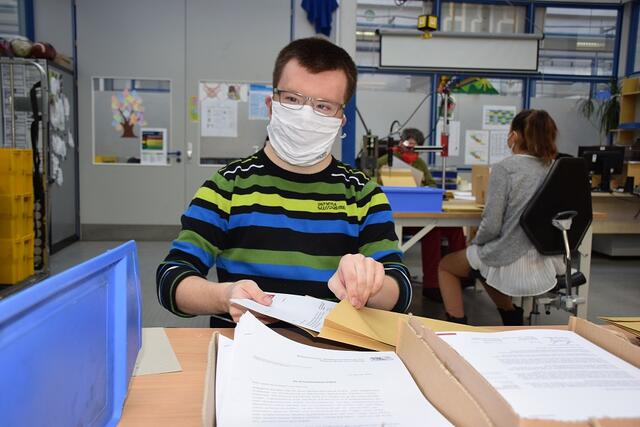 Mitarbeitende der noris inklusion verpacken FFP2-Masken für Bedürftige zum Versand.