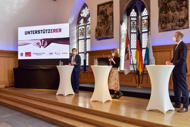 OB Marcus König und Niels Rossow stellen auf einer virtuellen Pressekonferenz im Historischen Rathaussaal die Kampagne „Nürnberg hält zamm“ vor. Mitte: Katharina Fritsch, Leitung Unternehmenskommunikation 1. FC Nürnberg. | Foto: Christine Dierenbach/Stadt Nürnberg
