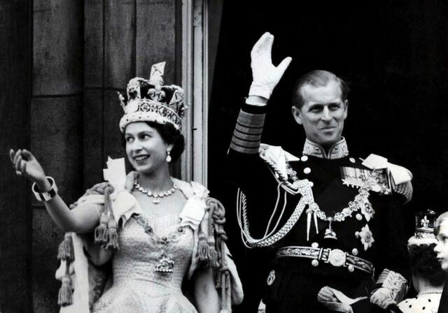 Königin Elizabeth II. von Großbritannien und ihr Mann Prinz Philip, Herzog von Edinburg (in der Uniform eines Marineadmirals) winken nach der prunkvollen Krönungszeremonie in der Westminster-Abtei vom Balkon des Buckingham Palasts (1953).