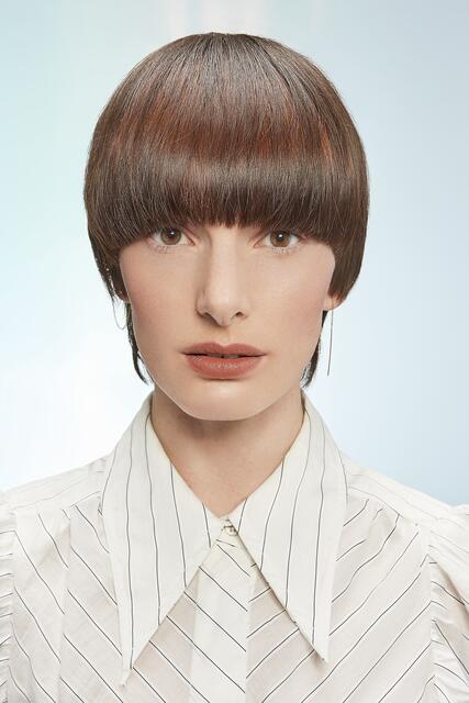 Der Bowl Cut erlebt 2021 ein ultimatives Level-up. Einen neuen Ausdruck erhält der Klassiker durch den längeren Nacken. Sehr feminin und lässig-elegant wirkt die glatte Version mit einem Long Pony, der bis über die Augenbrauen reicht. Für einen spannenden Effekt sorgt die kupferne Shine-Line im Vorderkopfbereich. Perfekt also für alle, die sich eine radikale Veränderung wünschen. | Foto: ZENTRALVERBAND DES DEUTSCHEN FRISEURHANDWERKS