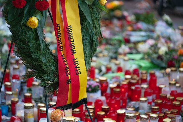 Trauerkerzen und Blumen, sowie ein Kranz der Stadt Würzburg, liegen am Tatort. | Foto: Nicolas Armer/dpa