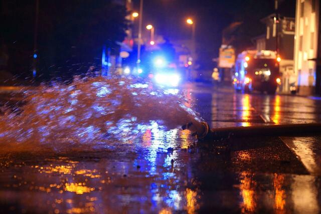 Wasser, das aus einem Keller in Erkrath gepumpt wurde, wird mit einem Feuerwehrschlauch auf die Straße geleitet. 
 | Foto: David Young/dpa