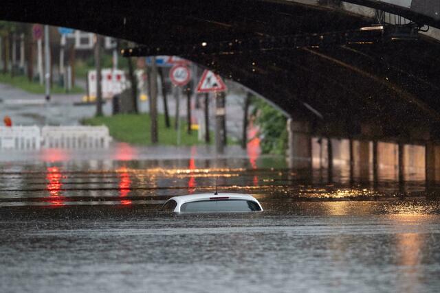 Nur das Dach eines Autos schaut noch aus dem Wasser, das eine Bahnunterführung in Köln geflutet hat.  | Foto: Marius Becker/dpa