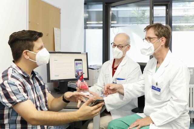 Studienteilnehmer Daniel Foydl (l.) im Gespräch mit Prof. Dr. Matthias Pauschinger (r.), dem Ärztlichen Leiter der Klinik für Innere Medizin mit dem Schwerpunkt Kardiologie, und Dr. Matthias Fittkau, Oberarzt der Klinik für Herzchirurgie und Leiter des Herzinsuffizienzprogrammes.