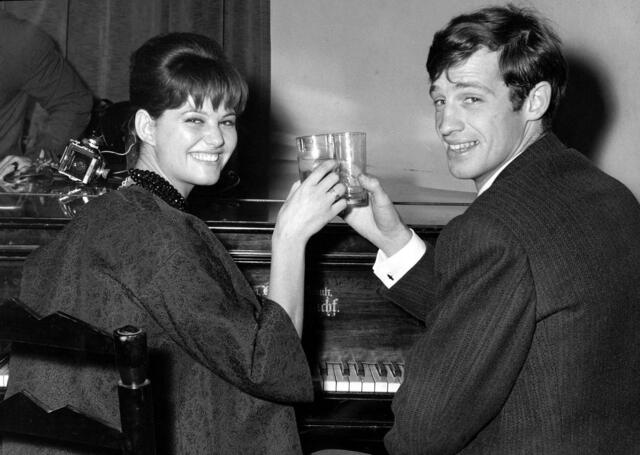 Der französische Schauspieler Jean-Paul Belmondo und die italienische Schauspielerin Claudia Cardinale stoßen an (1960). | Foto: Mario Torrisi/AP/dpa