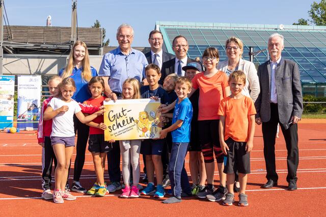 Bayerns Innenminister Joachim Herrmann  stellte auf dem Sportgelände des Post SV Nürnberg gemeinsam mit dem Präsidenten des Bayerischen Landessportverbandes, Jörg Ammon, dem 1. Landesschützenmeister des Bayerischen Sportschützenbundes, Christian Kühn, dem Präsidenten des Oberpfälzer Schützenbundes, Franz Brunner, und der Vizepräsidentin des Behinderten- und Rehabilitations-Sportverbands Bayern, Ria Engelhardt, das neue Gutscheinprogramm vor. Herrmann übergab dabei einen symbolischen Gutschein an eine Gruppe von Kindern.  | Foto: Norbert Wilhelmi/stmi