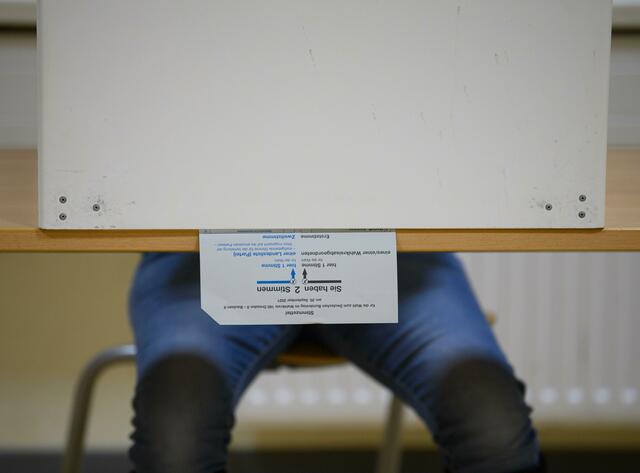 Ein Wählerin sitzt bei der Stimmabgabe zur Bundestagswahl im Wahllokal mit ihrem Stimmzettel in der Wahlkabine.  | Foto: Robert Michael/dpa-Zentralbild/dpa