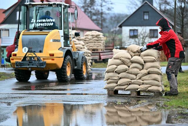 Freiwilligen Helfer verteilen Schleusinger Ortsteil Rappelsdorf in Thüringen Sandsäcke.  | Foto:  Martin Schutt/dpa-Zentralbild/dpa