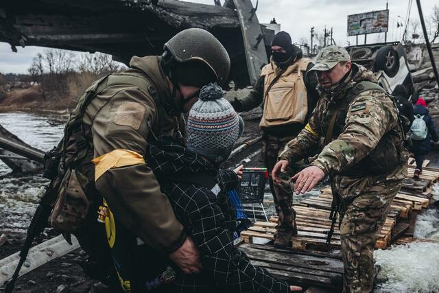 Soldaten helfen einem Kind beim Überqueren des Flusses in Irpin unweit von Kiew.