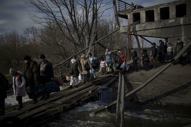 Auf der Flucht vor russischen Angriffen überqueren diese Ukrainer den Fluss Irpin unter einer zerstörten Brücke.