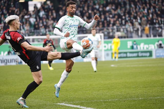 Der Fürther Timothy Tillman (r) und der Freiburger Nico Schlotterbeck (l) gehen mit gestreckten Beinen zum Ball. | Foto: Daniel Löb/dpa
