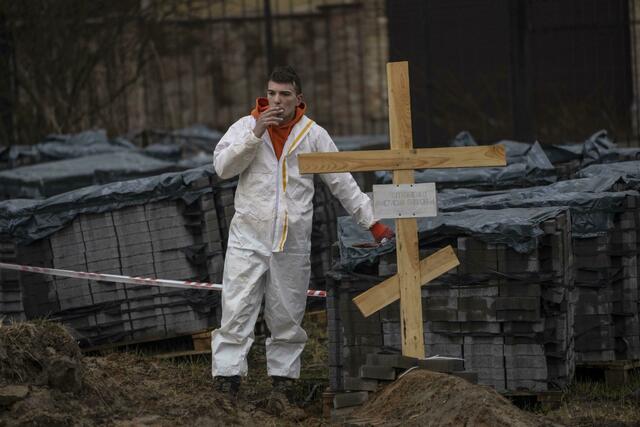 Ein Friedhofsarbeiter macht eine Pause von der Arbeit an einem Massengrab in Butscha. | Foto: Rodrigo Abd/AP/dpa