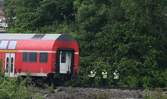 Polizisten stehen neben einem der Waggos auf dem Gleis.  | Foto: Angelika Warmuth/dpa