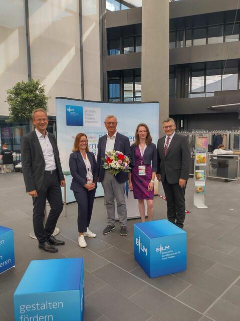 Medienminister und Leiter der Bayerischen Staatskanzlei Dr. Florian Herrmann, MdL, gratulierte Siegfried Schneider zur Ernennung zum neuen Medienstandortbotschafter beim 30-jährigigen Jubiläum der Lokalrundfunktage in Nürnberg. Von links: Dr. Thorsten Schmiege (BLM Präsident), Dr. Annette Schumacher (BLM Geschäftsführerin), Siegfried Schneider (Medienbotschafter), Lina Timm ( Medien.Bayern Geschäftsführerin) &amp; Dr. Florian Herrmann, MdL (Staatsminister für Medien). | Foto: Lokalrundfunktage/Medien.Bayern GmbH