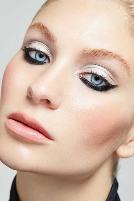 Der Reverse Cat Eye-Look hat die sozialen Medien im Sturm erobert. Der dunkle Kajalstrich wird dabei nämlich nicht auf dem Lid, sondern am unteren Wimpernkranz aufgetragen und nach oben zur Schläfe hin verblendet. Das bewegliche Lid hingegen wird mit einem silbernen Lidschatten für einen Metallic-Effekt stark geschminkt und bis unter die Augenbrauen weich verblendet. Die Wimpern werden kräftig mit schwarzer Mascara getuscht. Zum Abschluss werden die Lippen in einem Nudeton geschminkt und der Teint mit einem Hauch Rouge in Bronze aufgefrischt. | Foto: ZENTRALVERBAND DES DEUTSCHEN FRISEURHANDWERKS