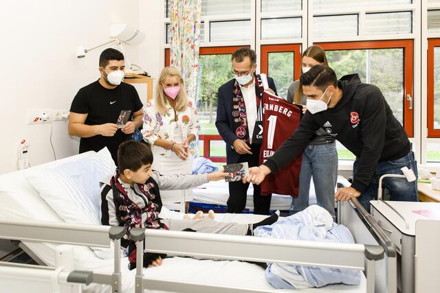 Ein Club-Schal samt Autogramm für Eyem: Karin Baumüller-Söder und der 1. FCN brachten Geschenke ins Klinikum Nürnberg. Mit von der Partie waren unter anderem Club-Spieler Christopher Schindler sowie die FCN-Spielerin Saskia Bürki und Prof. Dr. Achim Jockwig, Vorstandsvorsitzender des Klinikums Nürnberg.  | Foto: Uwe Niklas/Klinikum Nürnberg