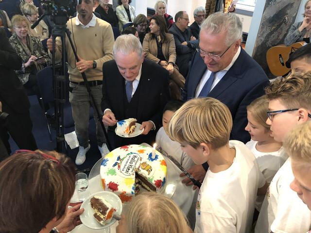 5 Jahre „Hallo Klexi – wir lernen Deutsch“ wurden mit einer großen Geburtstagstorte gefeiert. Hans-Peter Schmidt, Vorsitzender des Stiftungsrats der Stiftung Nürnberger Versicherung, und Joachim Herrmann, Bayerischer Innenminister, erhielten die ersten Stücke.  | Foto: Nürnberger Versicherung