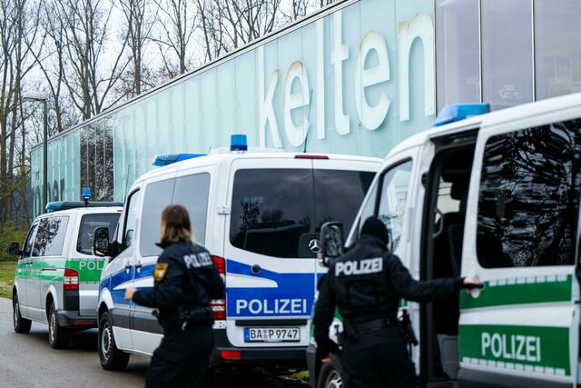 Einsatzkräfte der Bereitschaftspolizei steigen vor dem Kelten Römer Museum aus ihren Fahrzeugen aus.  | Foto: Lennart Preiss/dpa