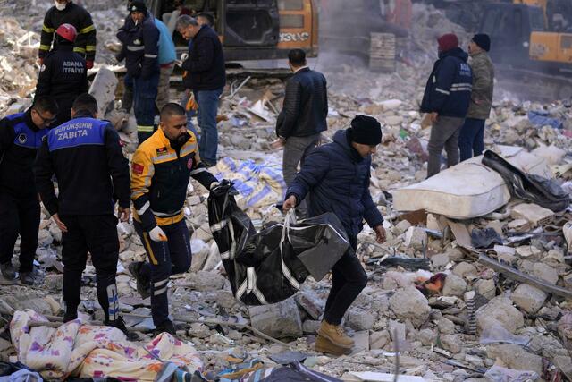 Zwei Männer tragen eine Leiche aus einem zerstörten Gebäude im türkischen Adana. | Foto: Hussein Malla/AP/dpa