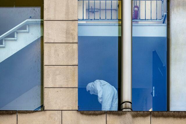 Eine Beamtin der Polizei untersucht in Schutzkleidung das Treppenhaus.  | Foto: Christoph Reichwein/dpa